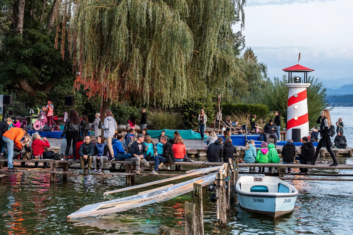 Das Organisationskomitee beschreibt das Open Air am Greifensee als «klein, aber fein». (Archiv) Man sieht Menschen, die auf einem Steg am Open Air am Greifensee sitzen.